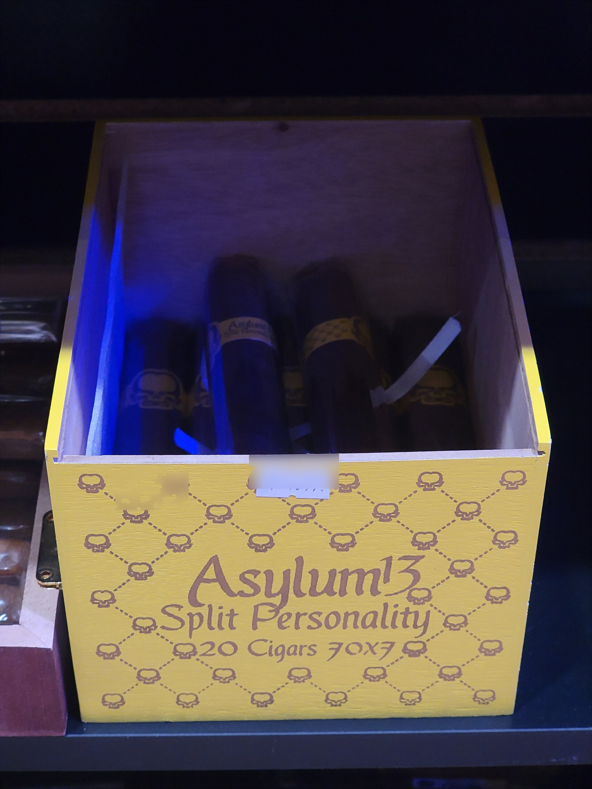 A yellow Asylum 13 Split Personality box open on the humidor shelf