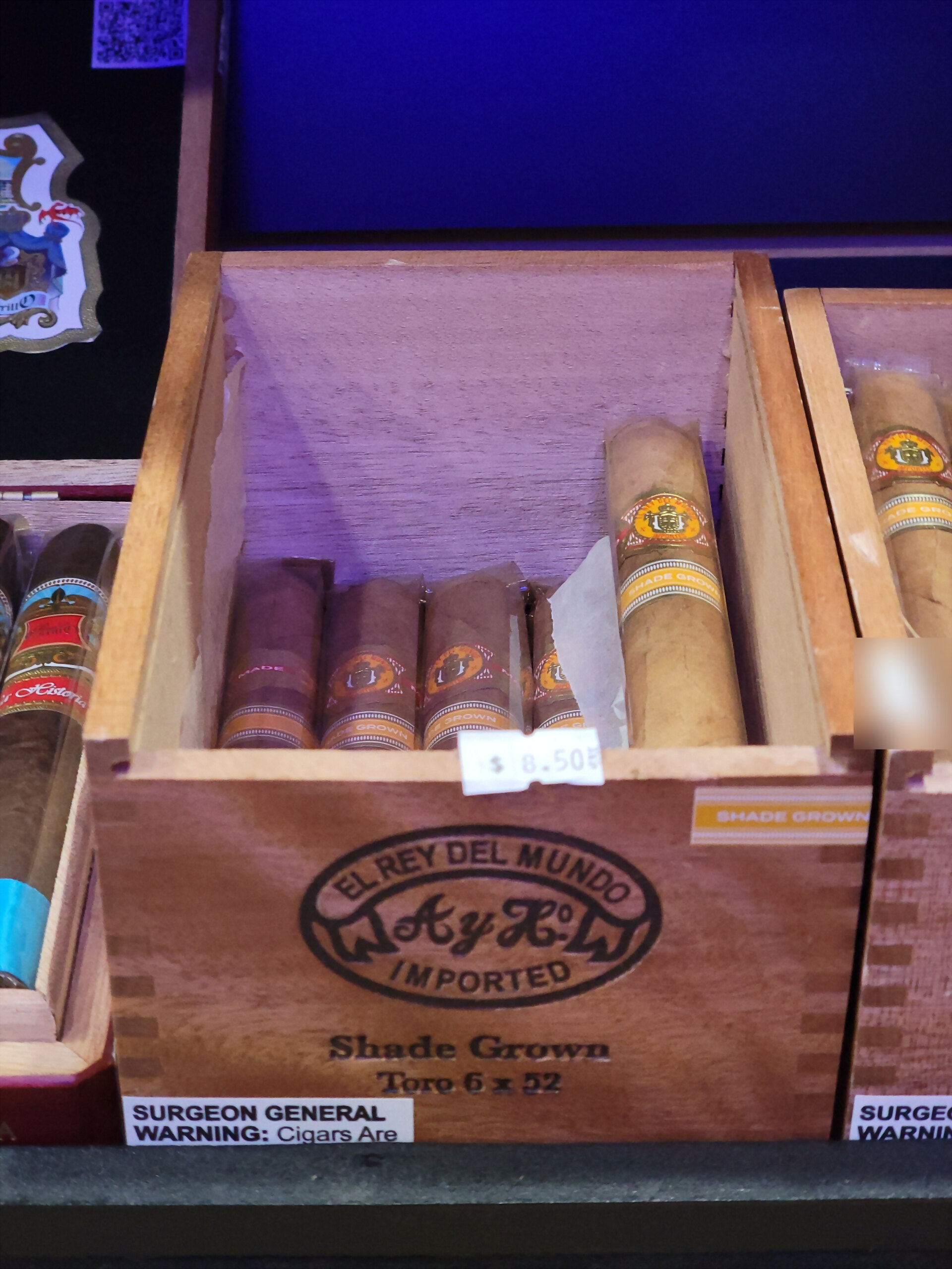 An El Rey del Mundo Shade Grown box, Toro 6 x 52 beneath the A y H oval