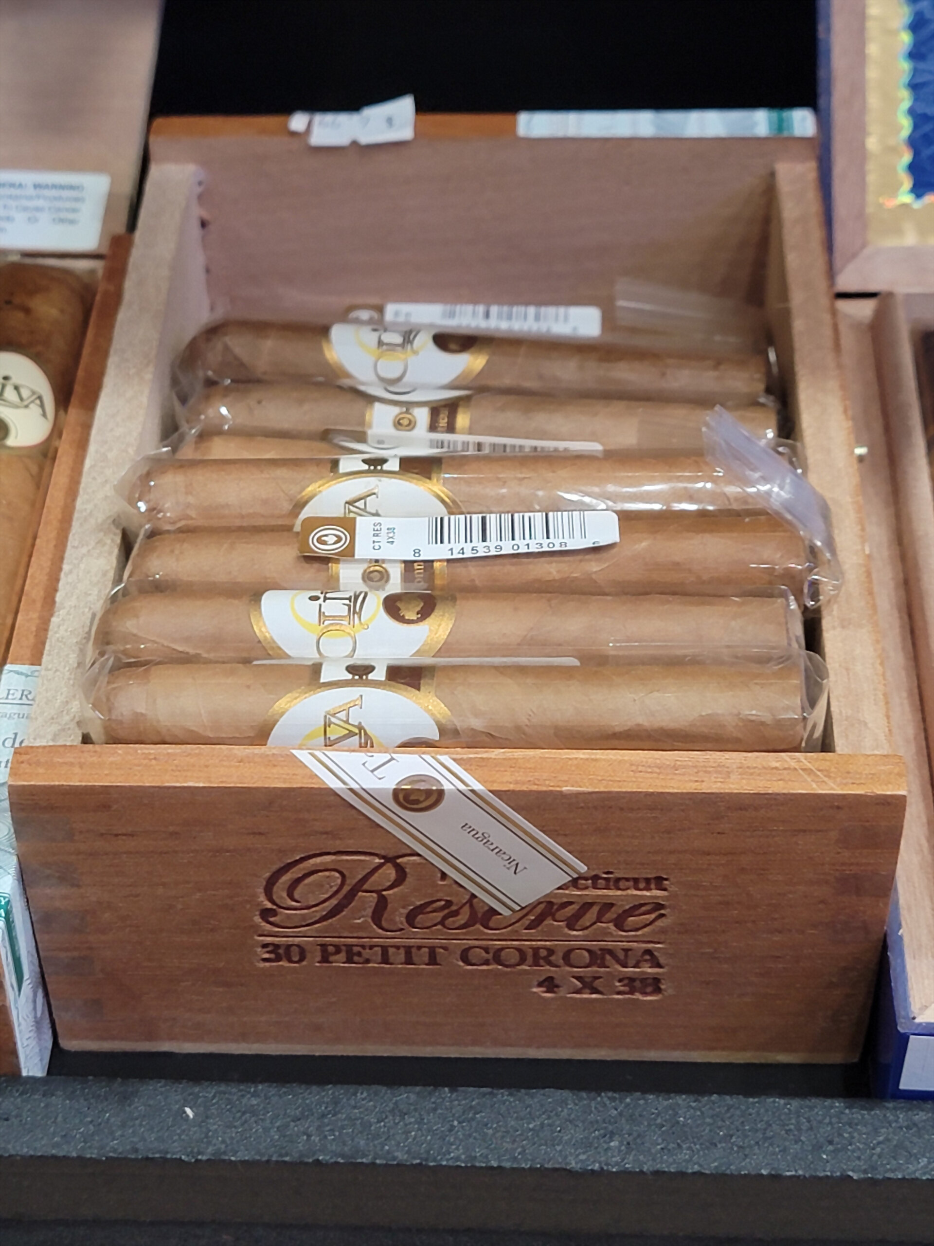 An Oliva Connecticut Reserve box open on the shelf, 30 PETIT CORONA 4 X 38 burned into the front