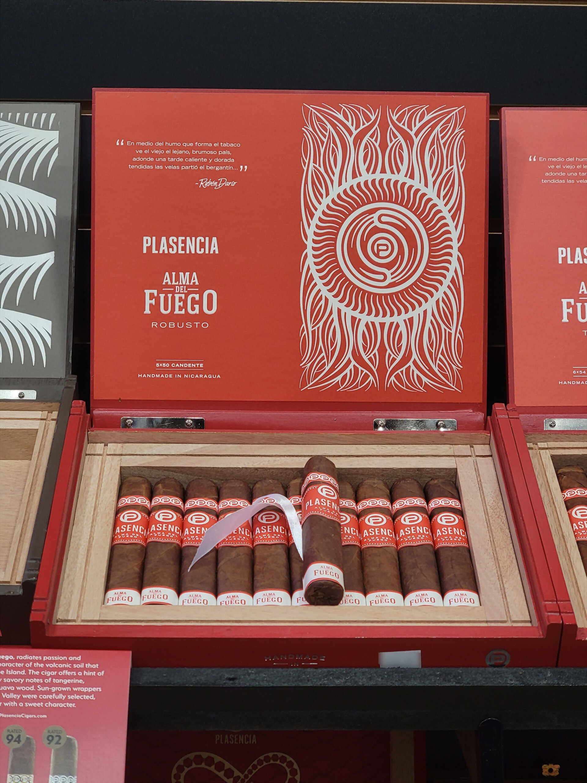 A red Plasencia Alma del Fuego Robusto box open on the humidor shelf