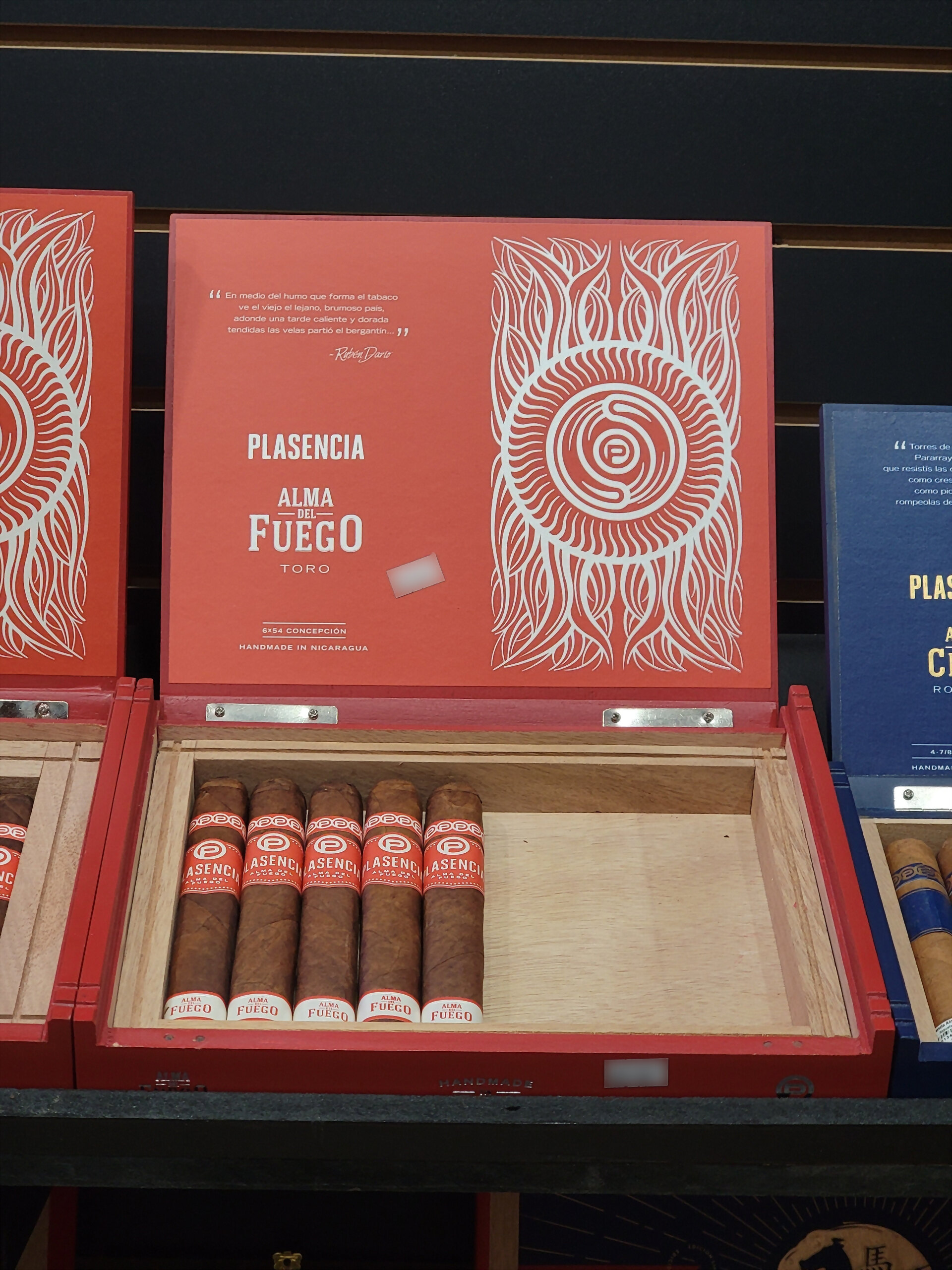 A red Plasencia Alma del Fuego Toro box, lid raised, showing the white sun artwork